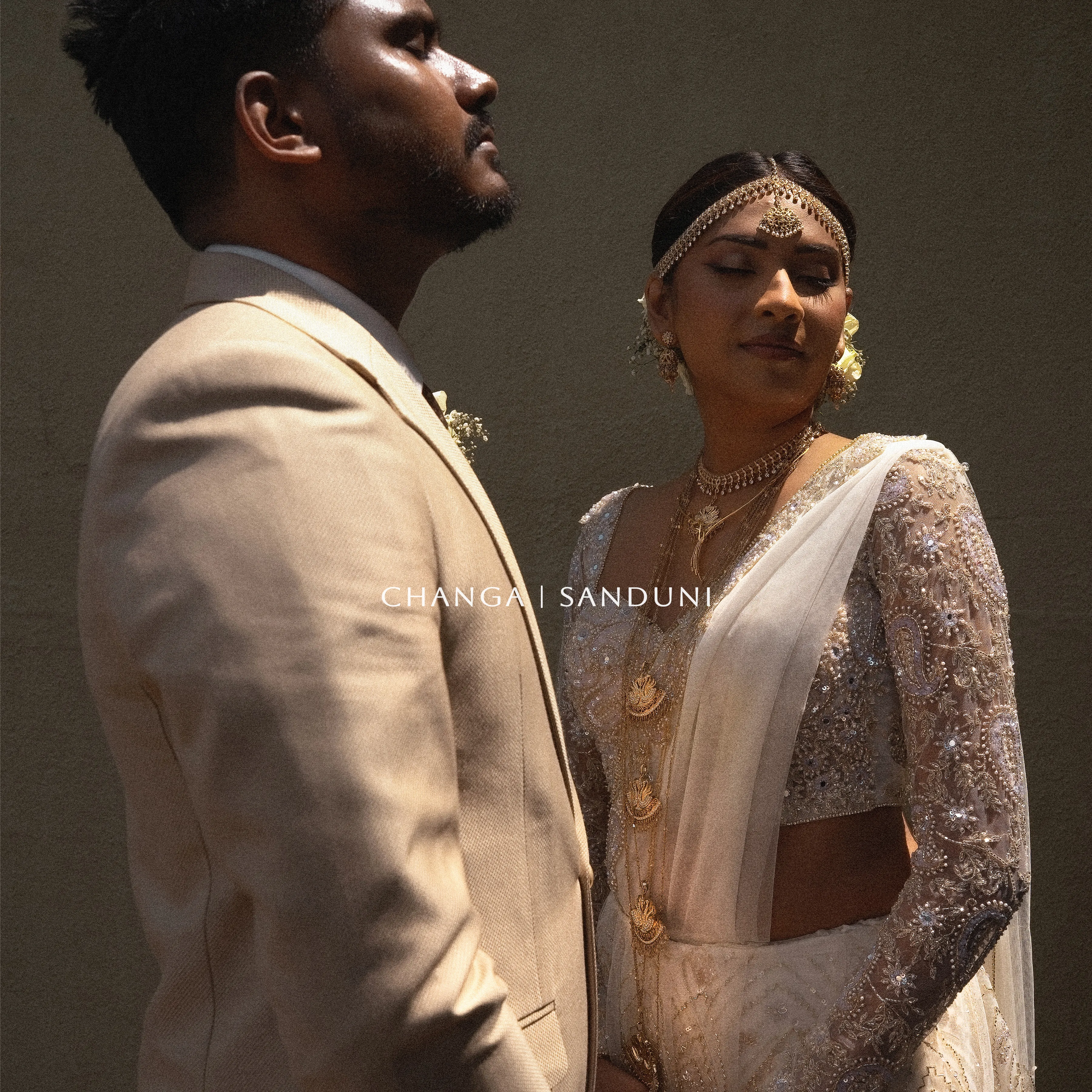 Changa and Sanduni stand together in intricately embroidered Kandyan wedding attire.