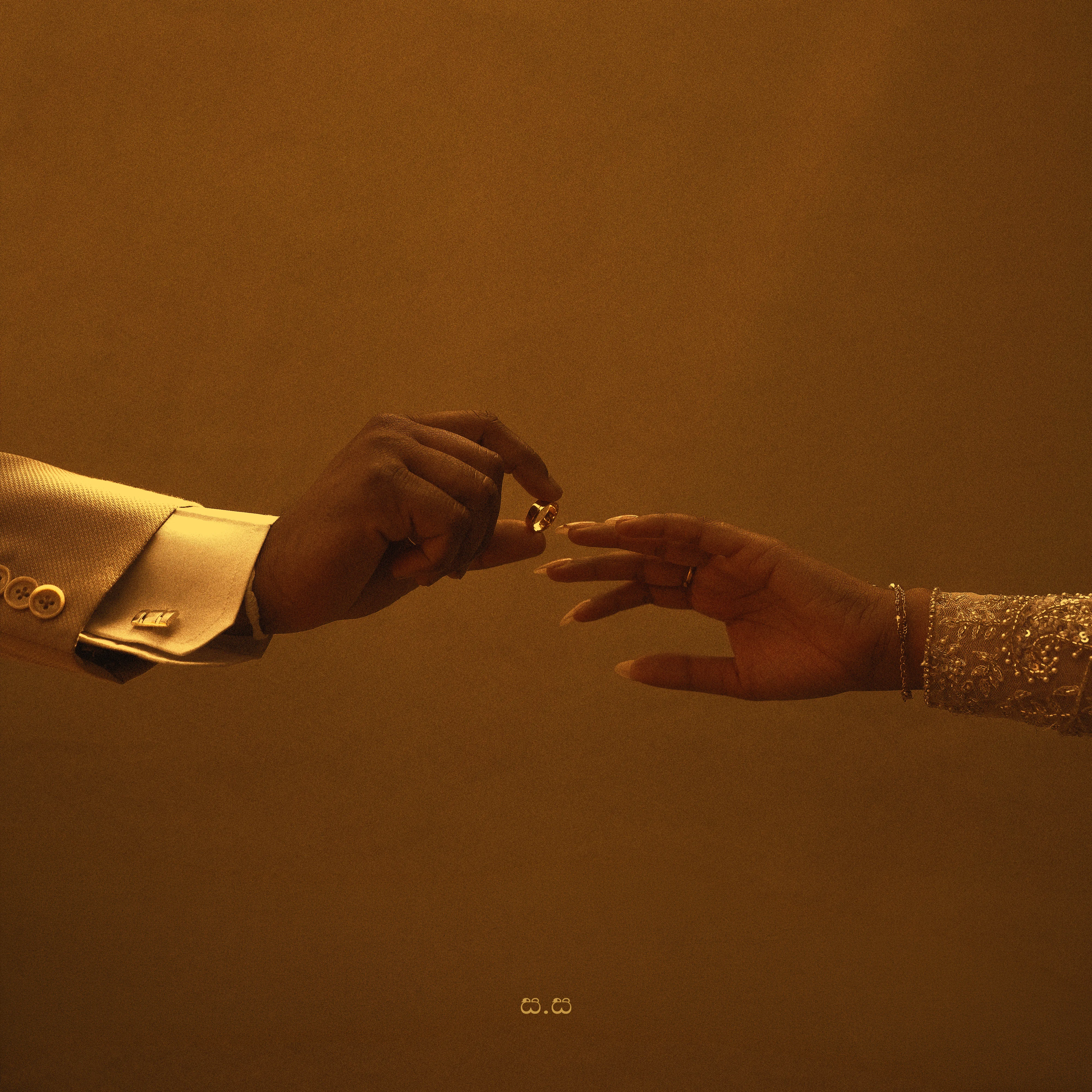 The couple reach toward one another in a warm, minimal study of their hands.
