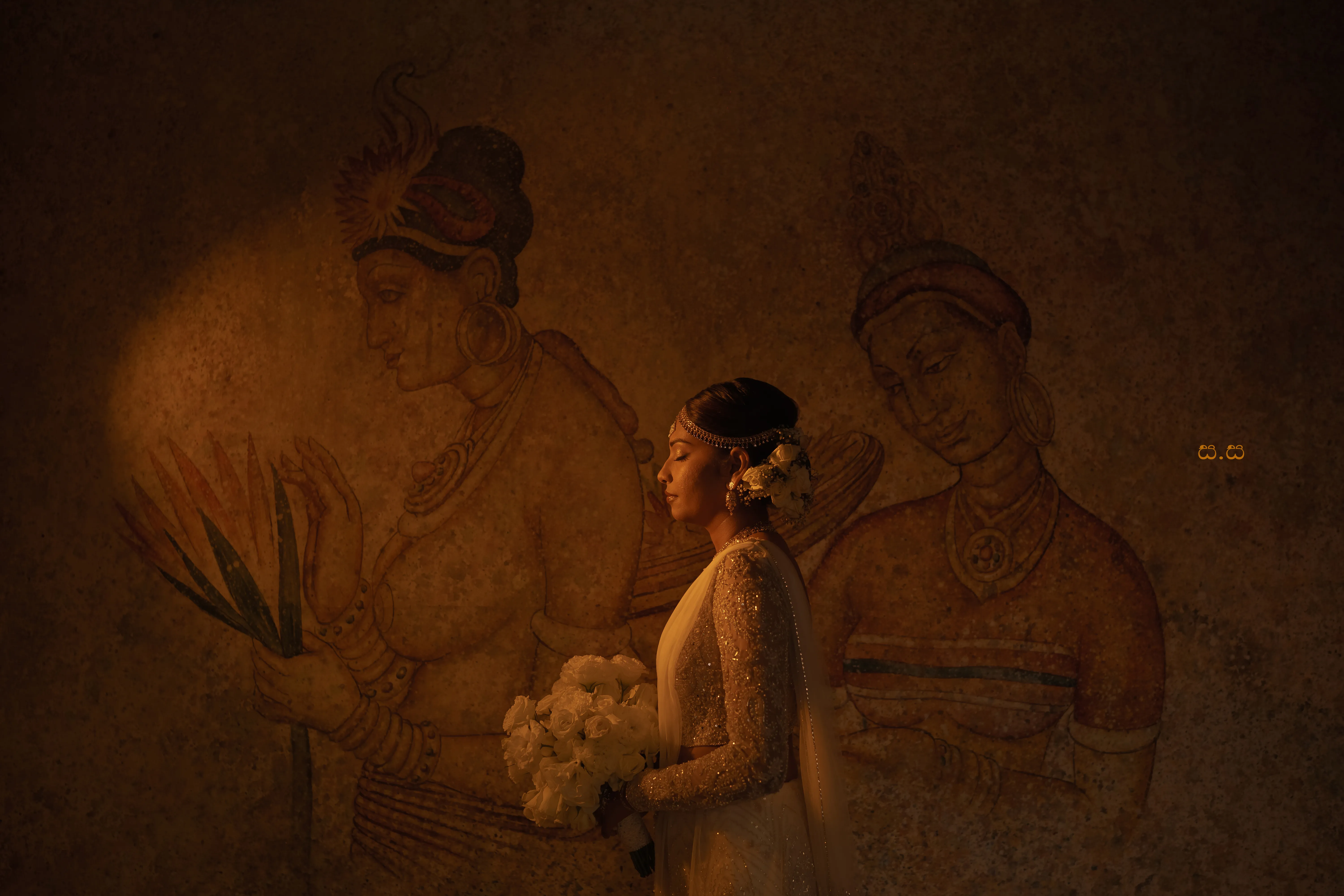 Sanduni poses beside a warm-toned mural of traditional figures.