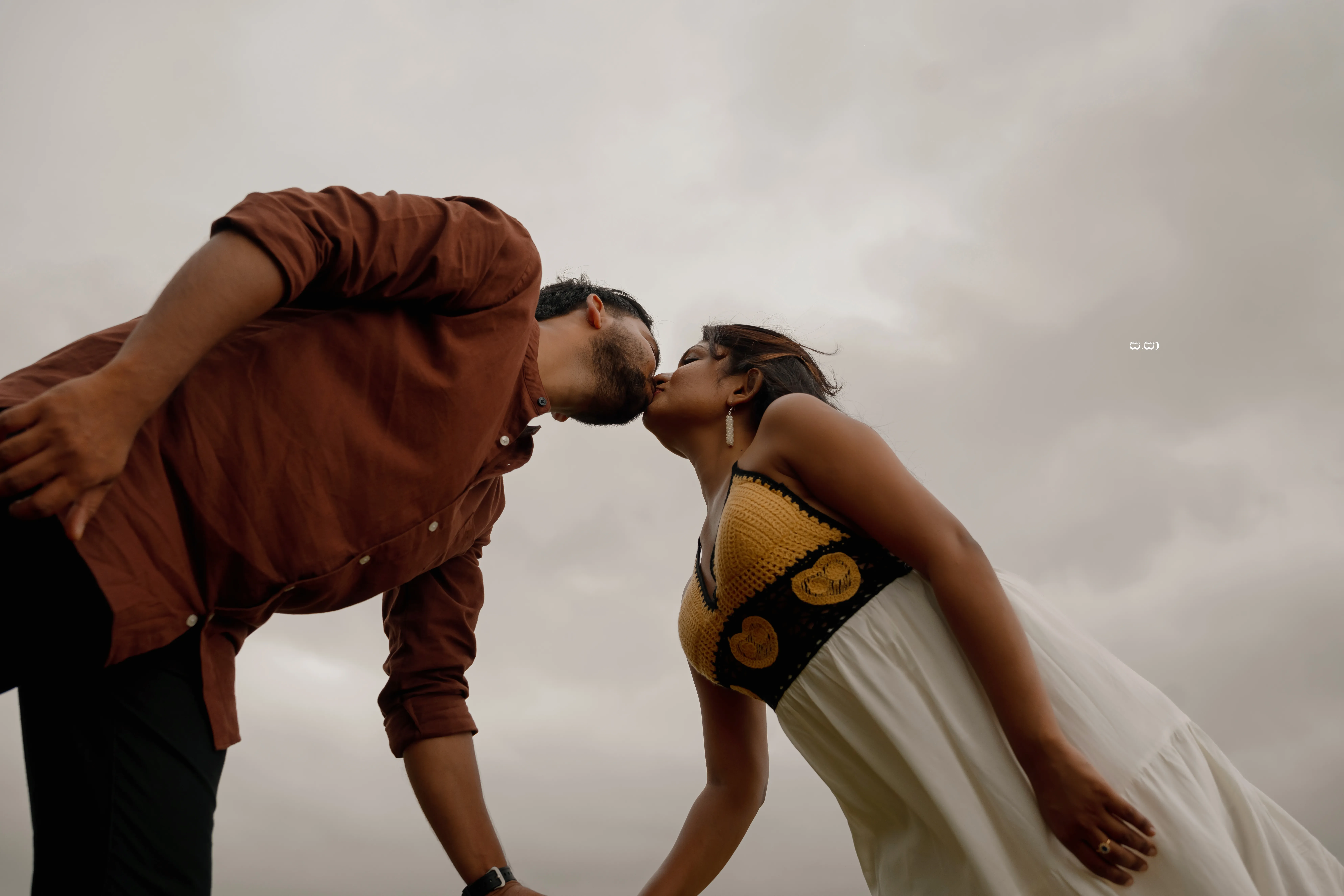 Charith and Lakshani lean toward one another in a low-angle portrait.