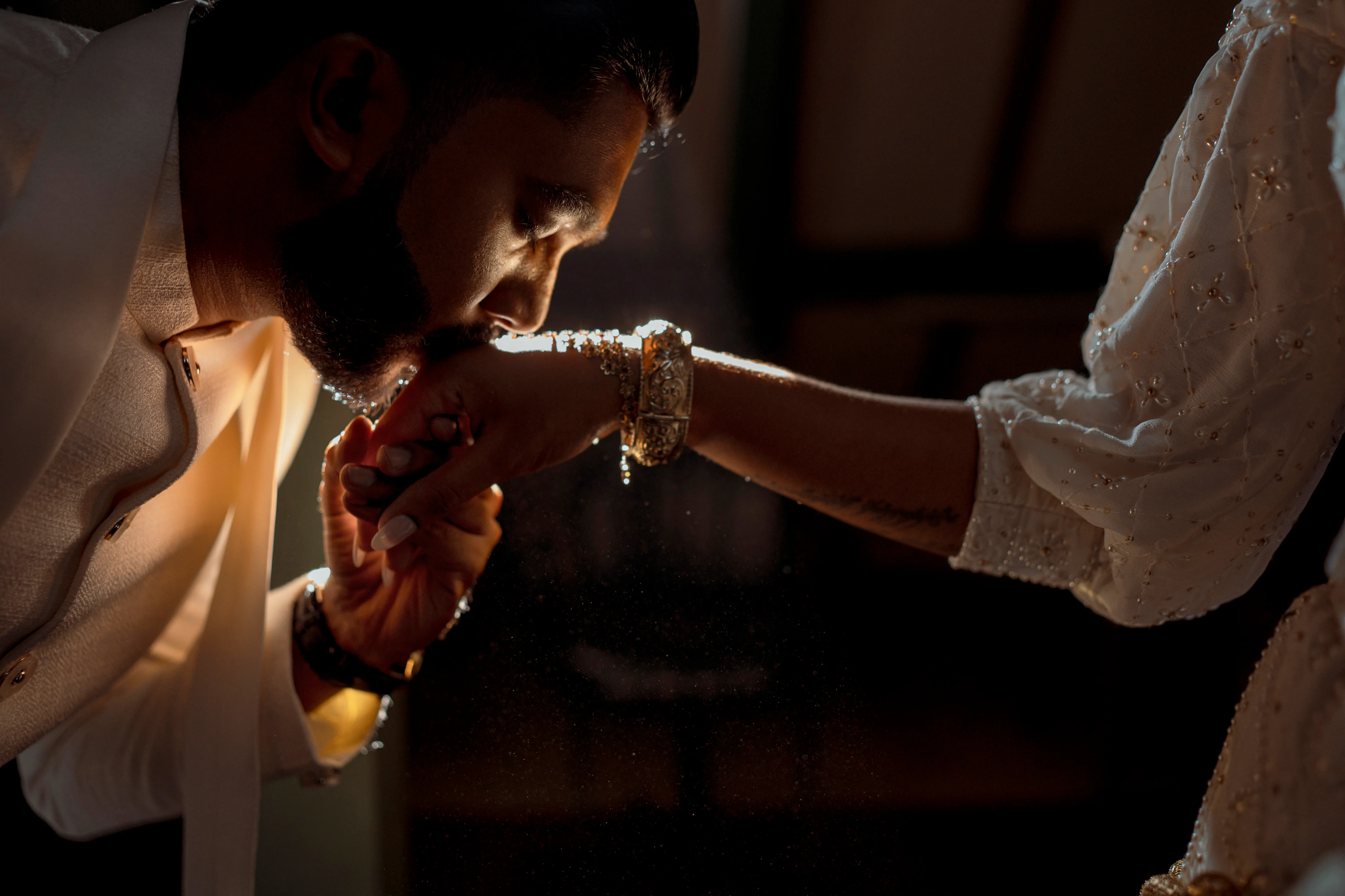 Mewan gently kisses Chathuri’s hand in a warm indoor portrait.