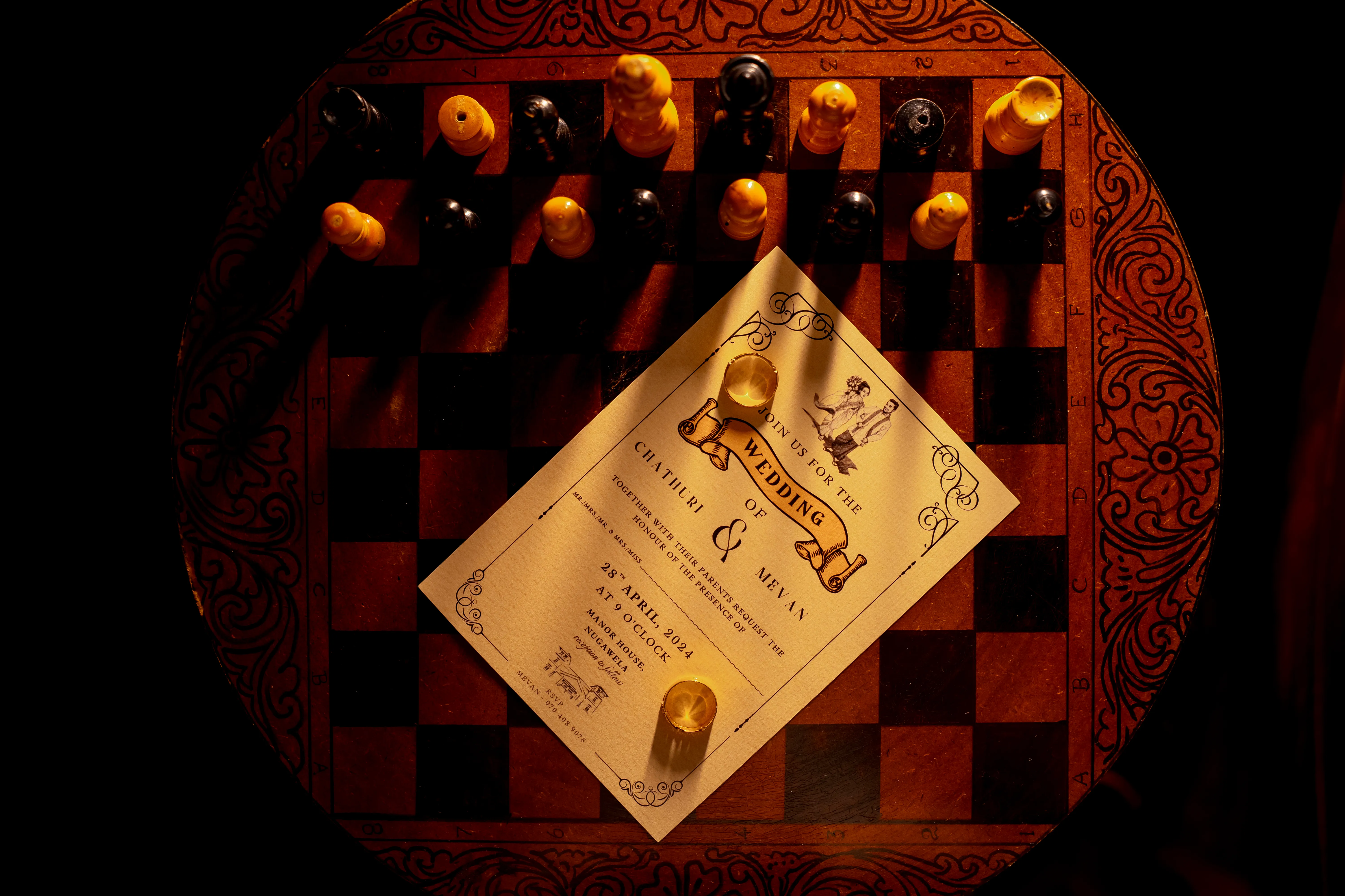 The wedding invitation rests beneath the rings in a richly styled flat lay.