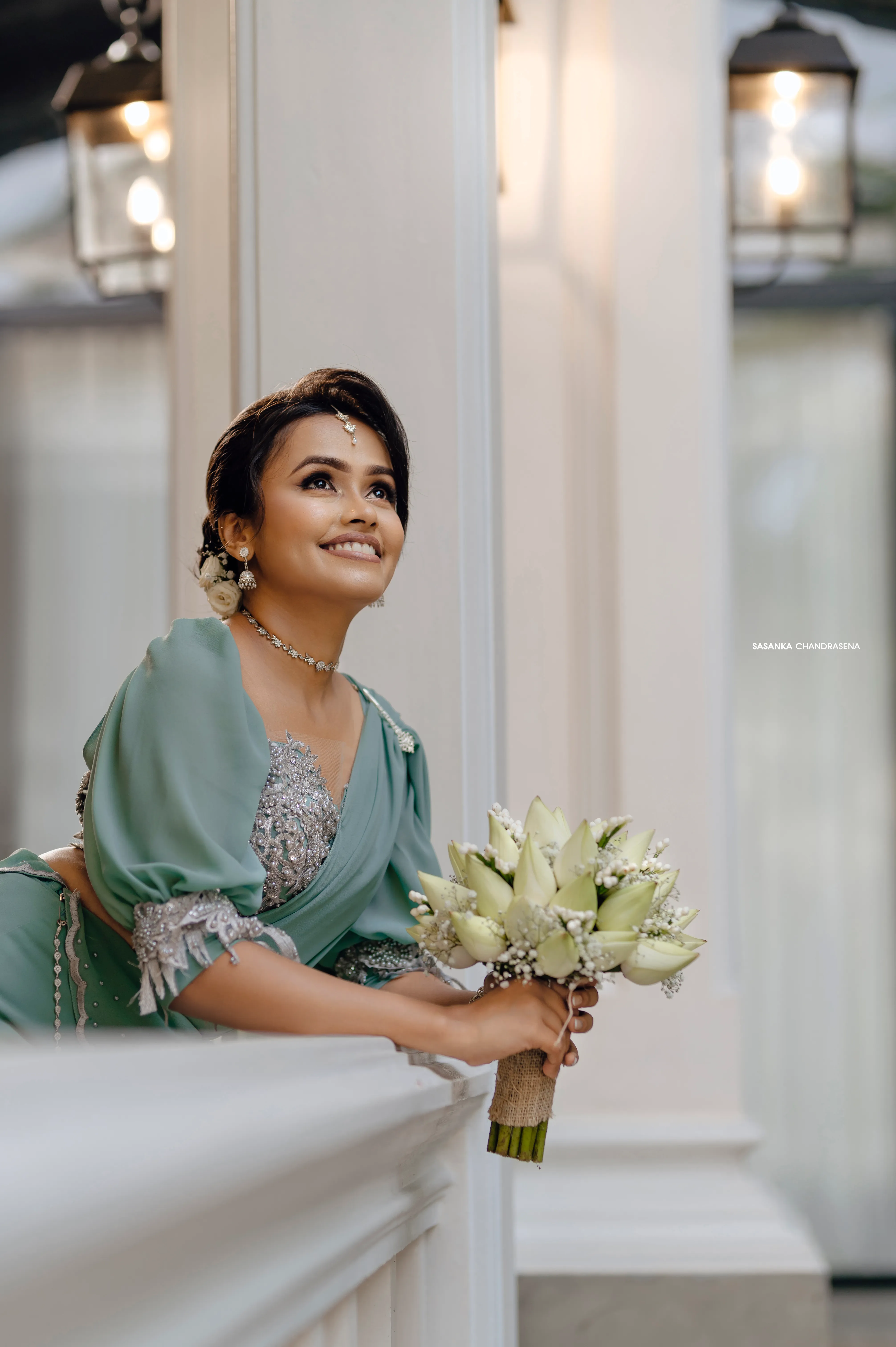 The bride-to-be looks toward soft window light beside the villa veranda.