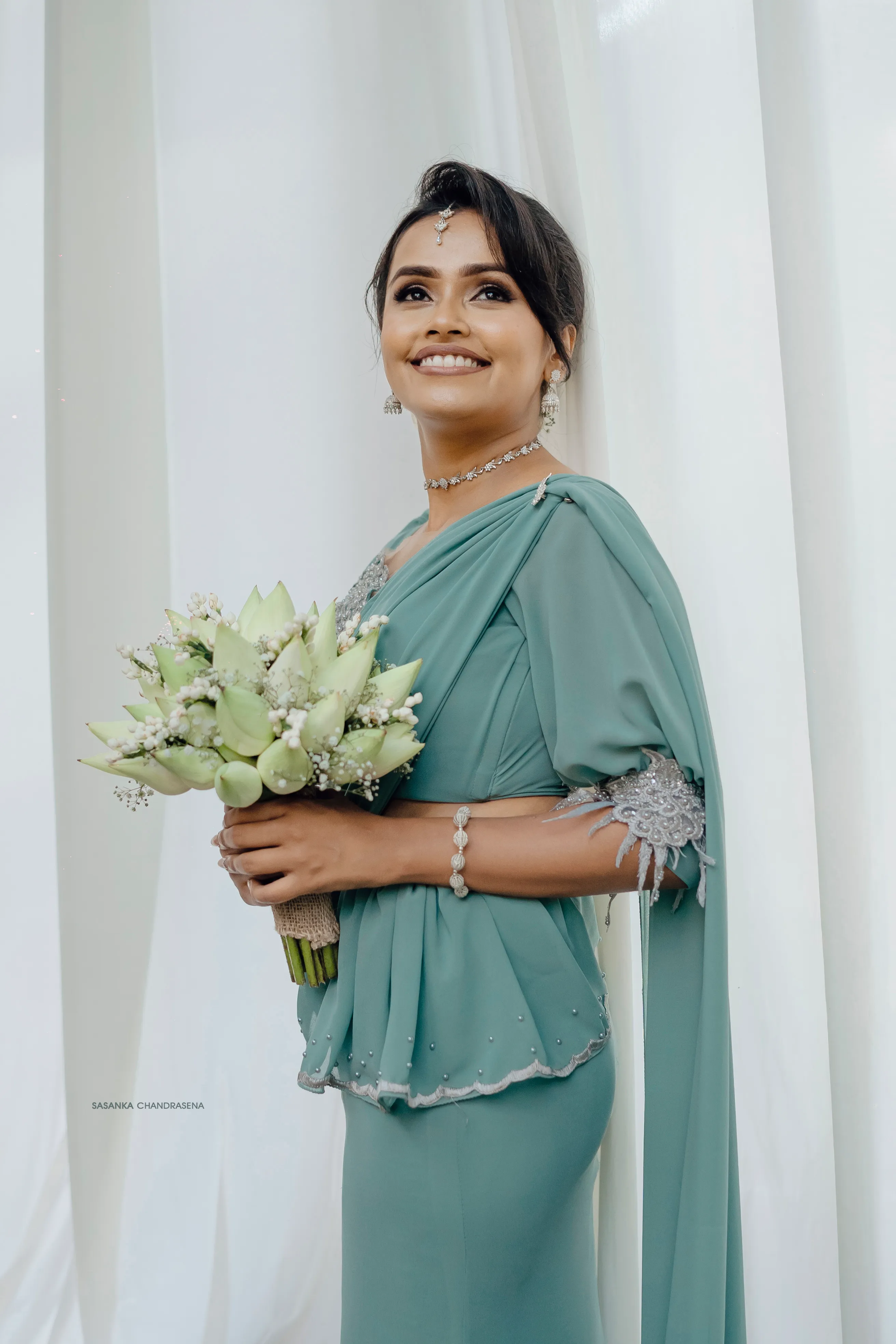 The bride-to-be holds an ivory bouquet against a clean white backdrop.