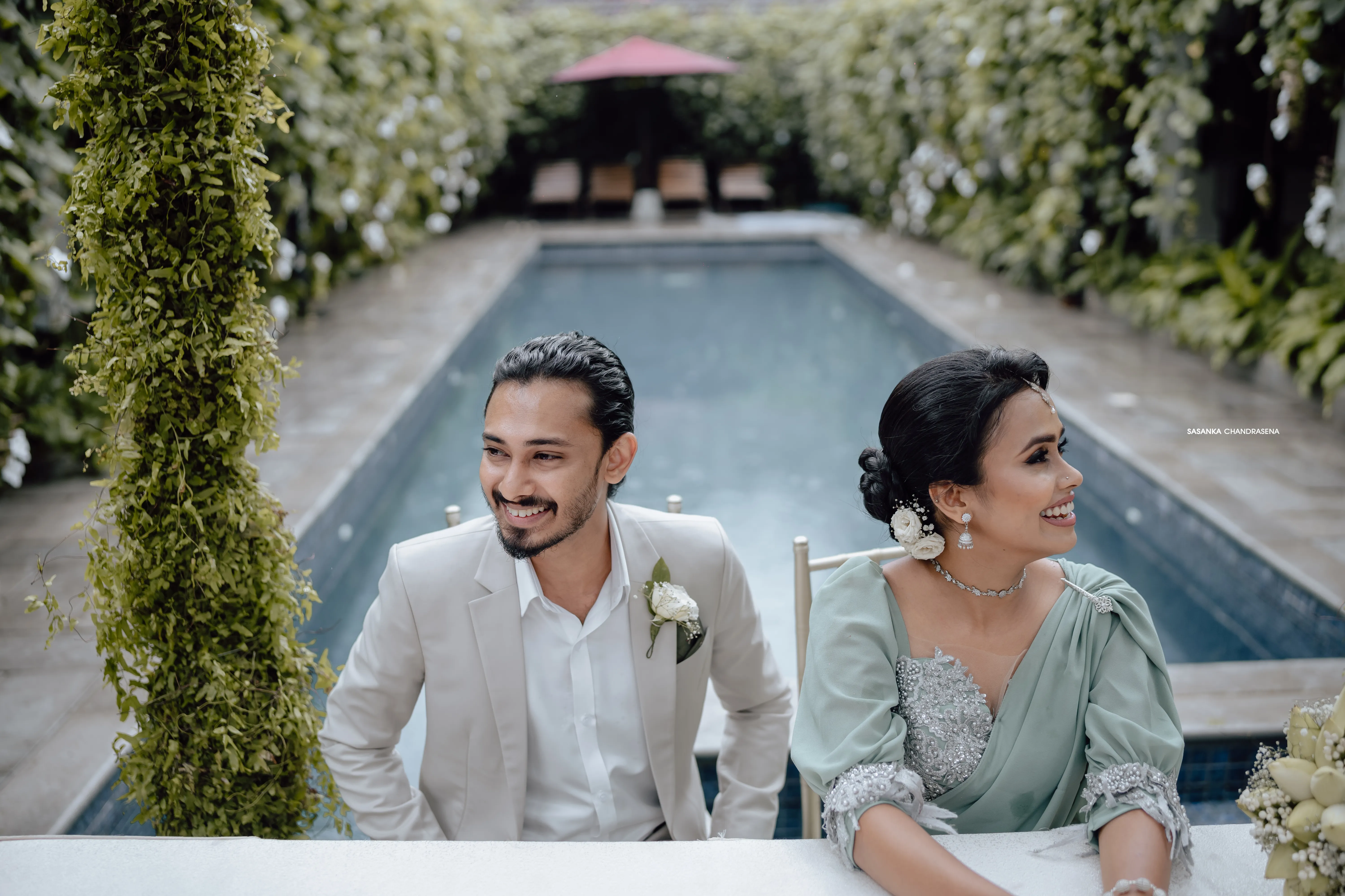 The couple shares a relaxed portrait beside the villa swimming pool.