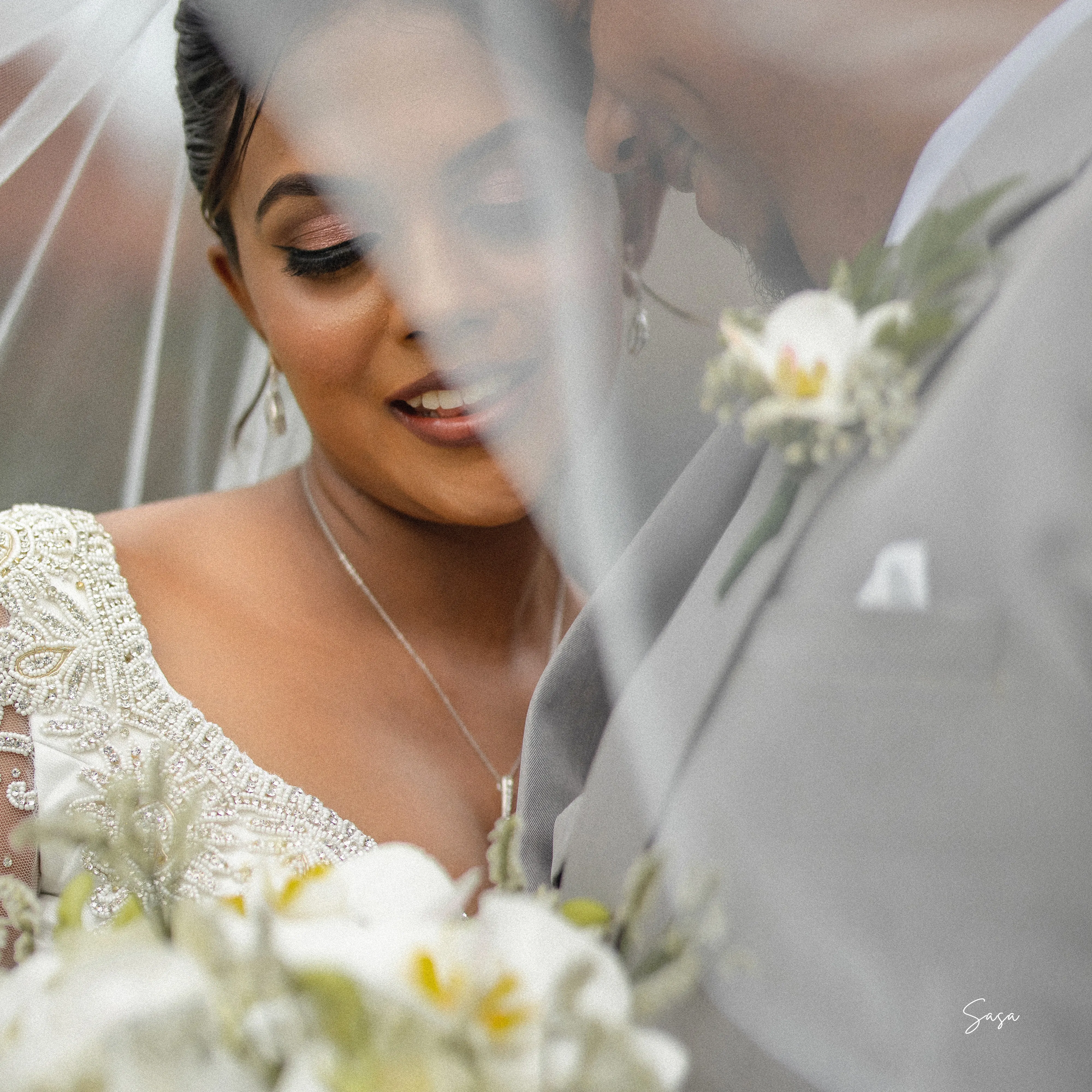 A close portrait frames Harindi’s lace dress, pendant, and white bouquet.