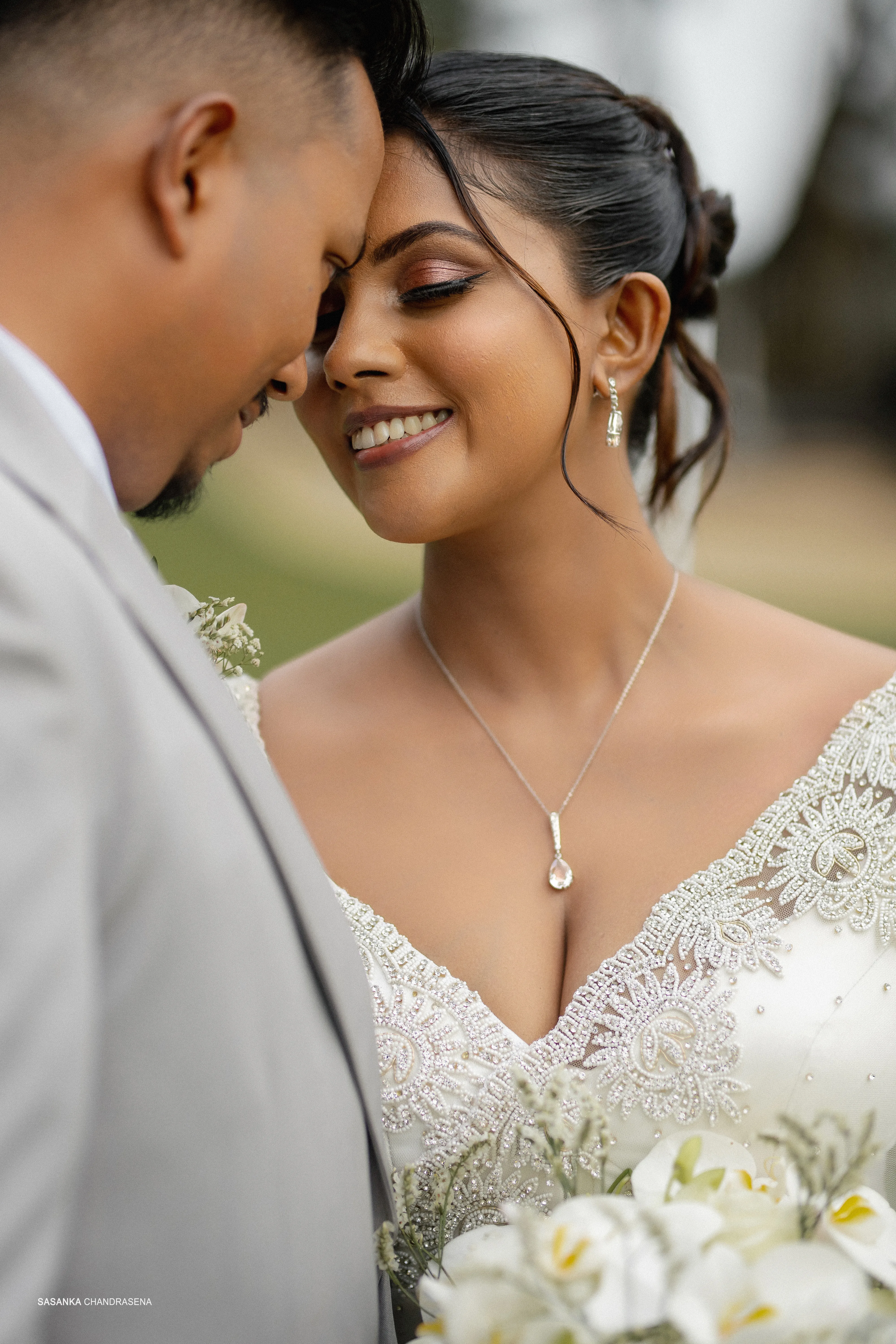 A close detail highlights Harindi’s pendant, embroidered neckline, and bouquet.