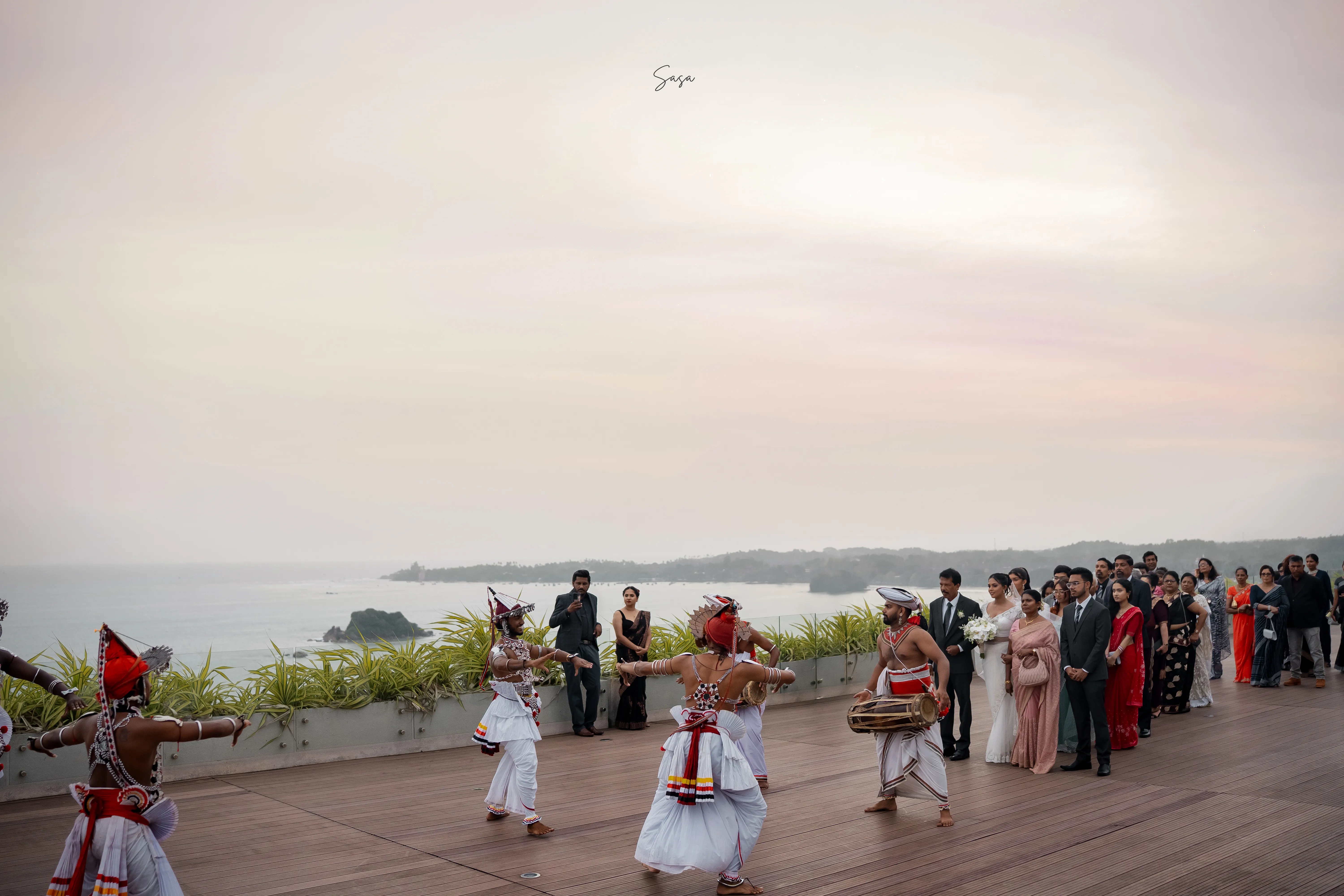 Traditional performers lead the celebration along a terrace overlooking the sea.
