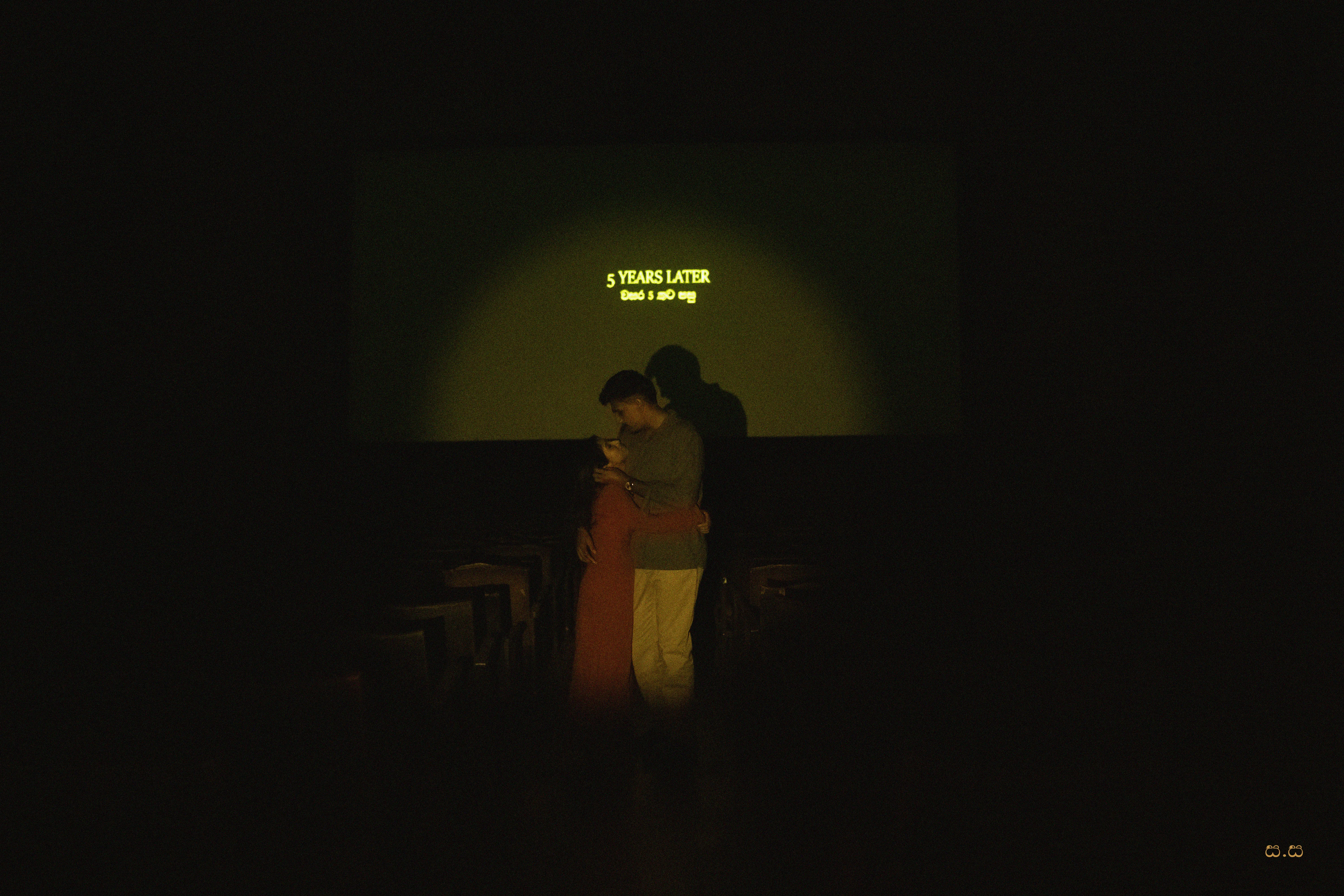 The couple appears as a small silhouette beneath a vintage screen projection.