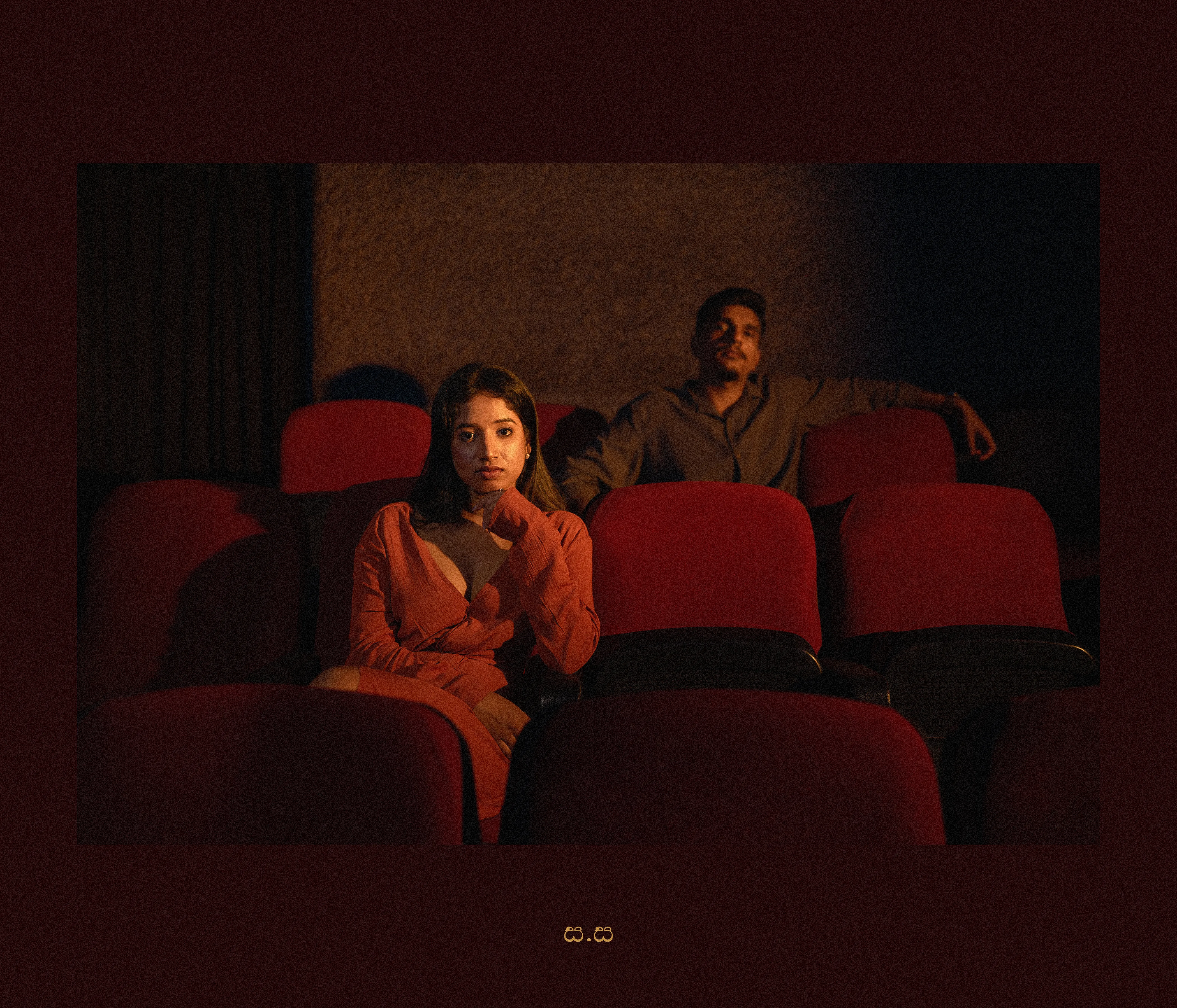 Hiruma and Naveen sit apart in the deep red seats of an old cinema.