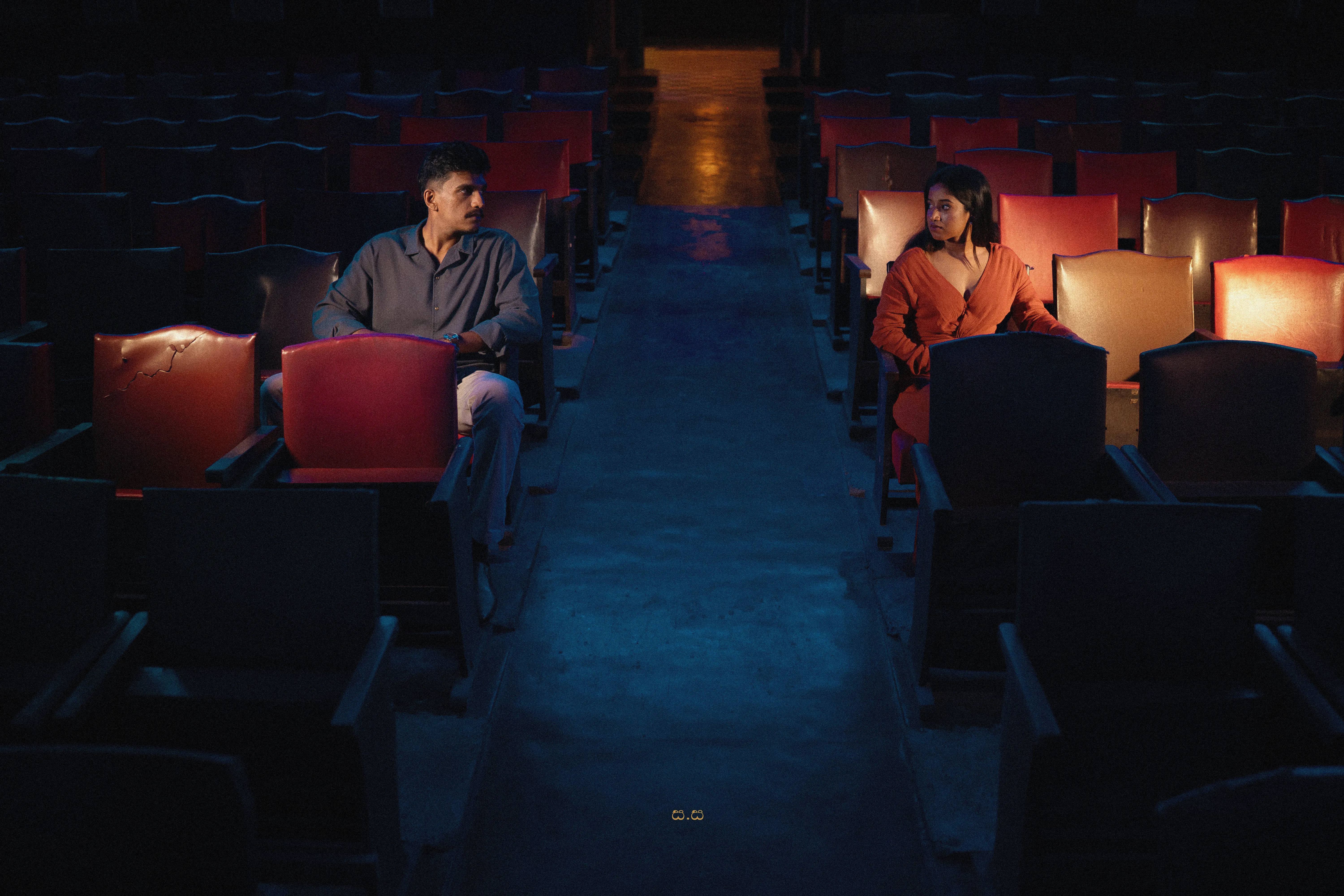 The couple face one another from opposite sides of the empty theatre.