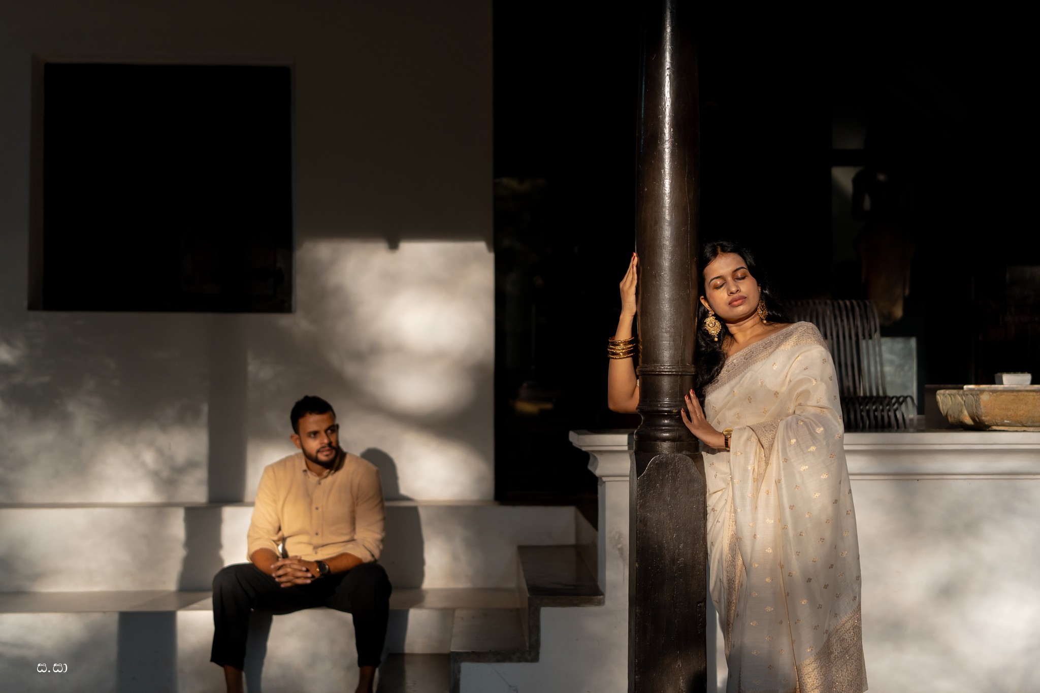 The couple occupies separate pools of light along the old shaded veranda.