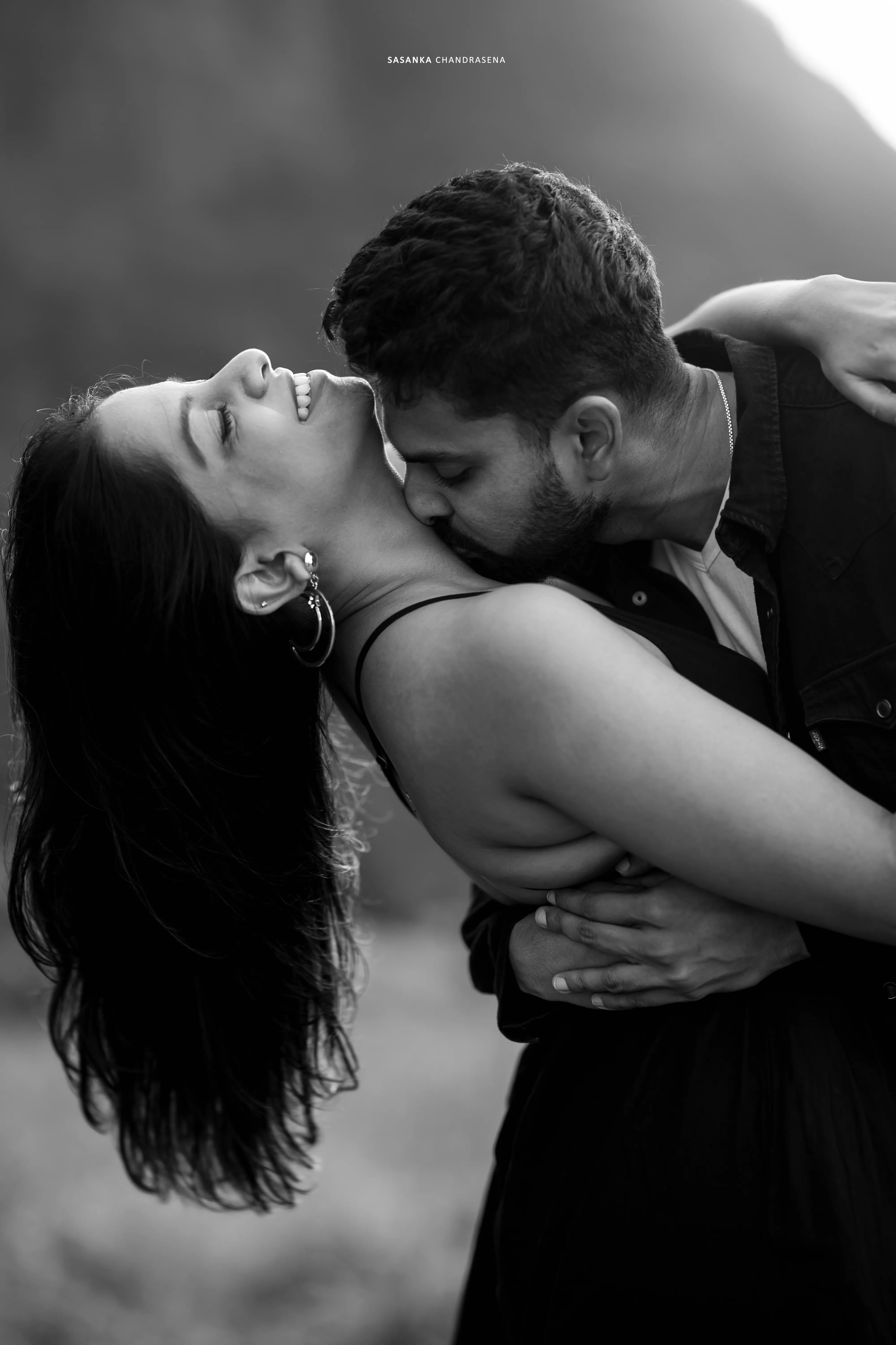 Iruka kisses Vidushi’s forehead in a close black-and-white mountain portrait.