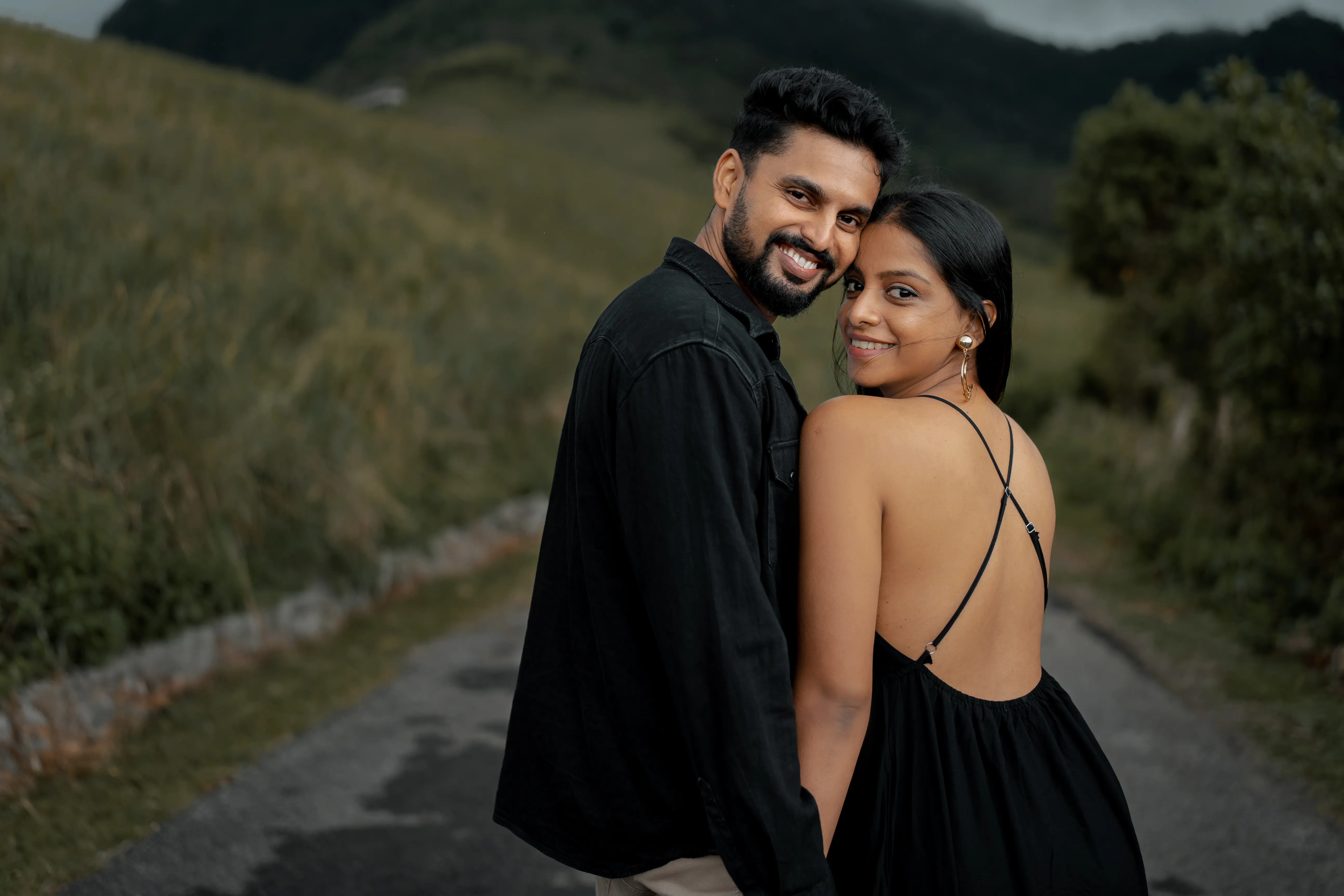 The couple embraces on an empty road winding through the highlands.