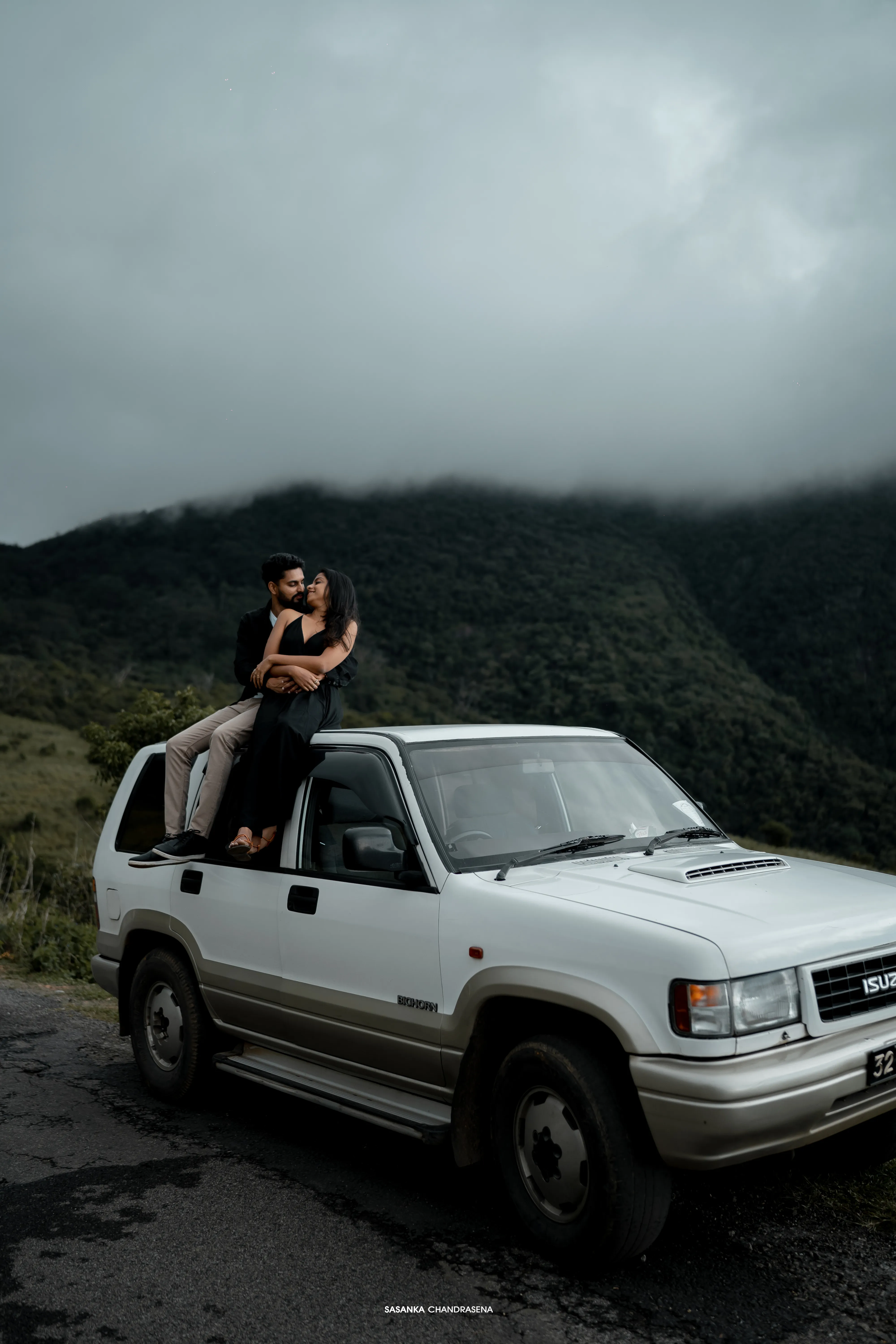 Iruka and Vidushi sit together atop a classic white four-wheel drive.