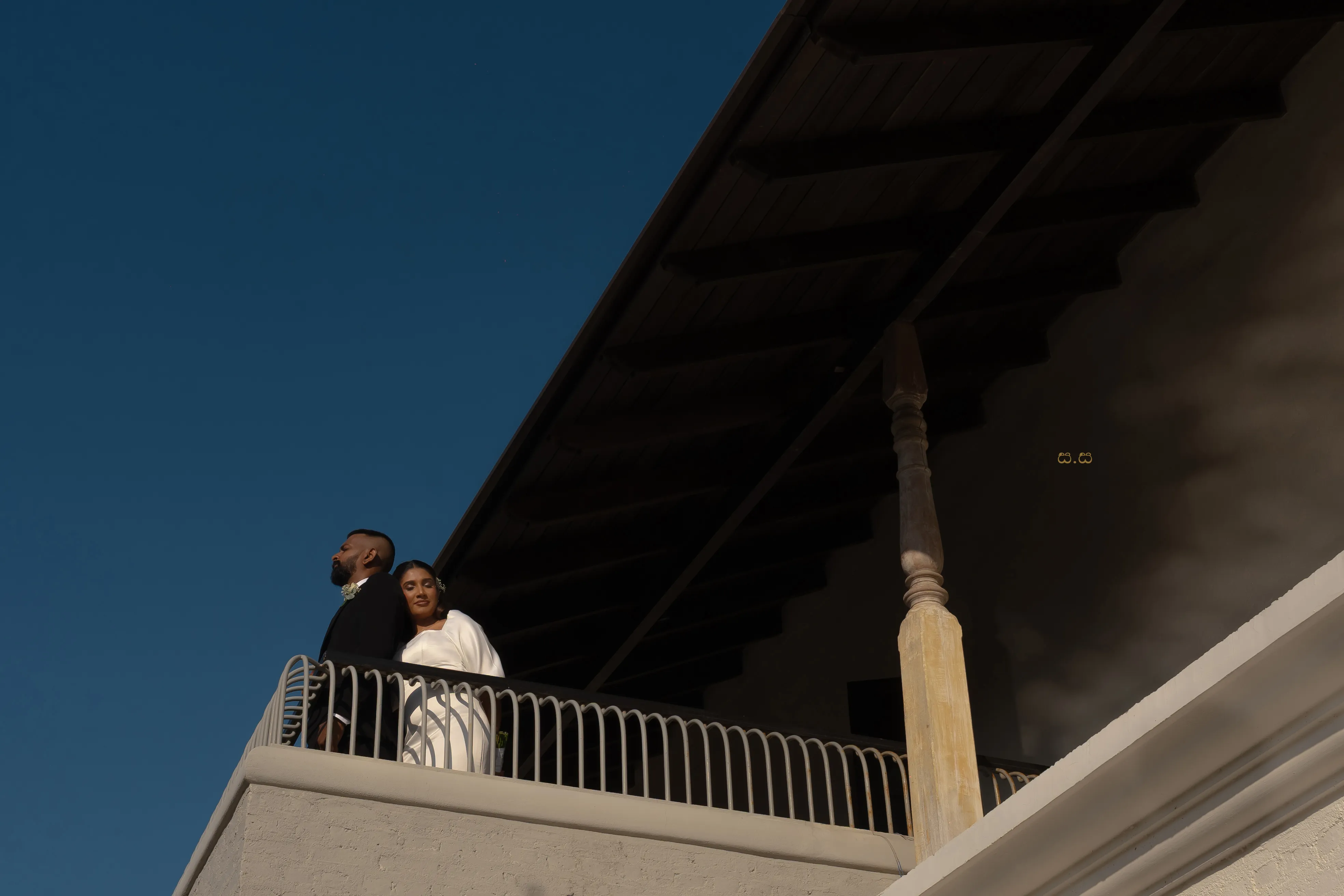 Malki and Erik appear beneath a strong roofline and clear evening sky.