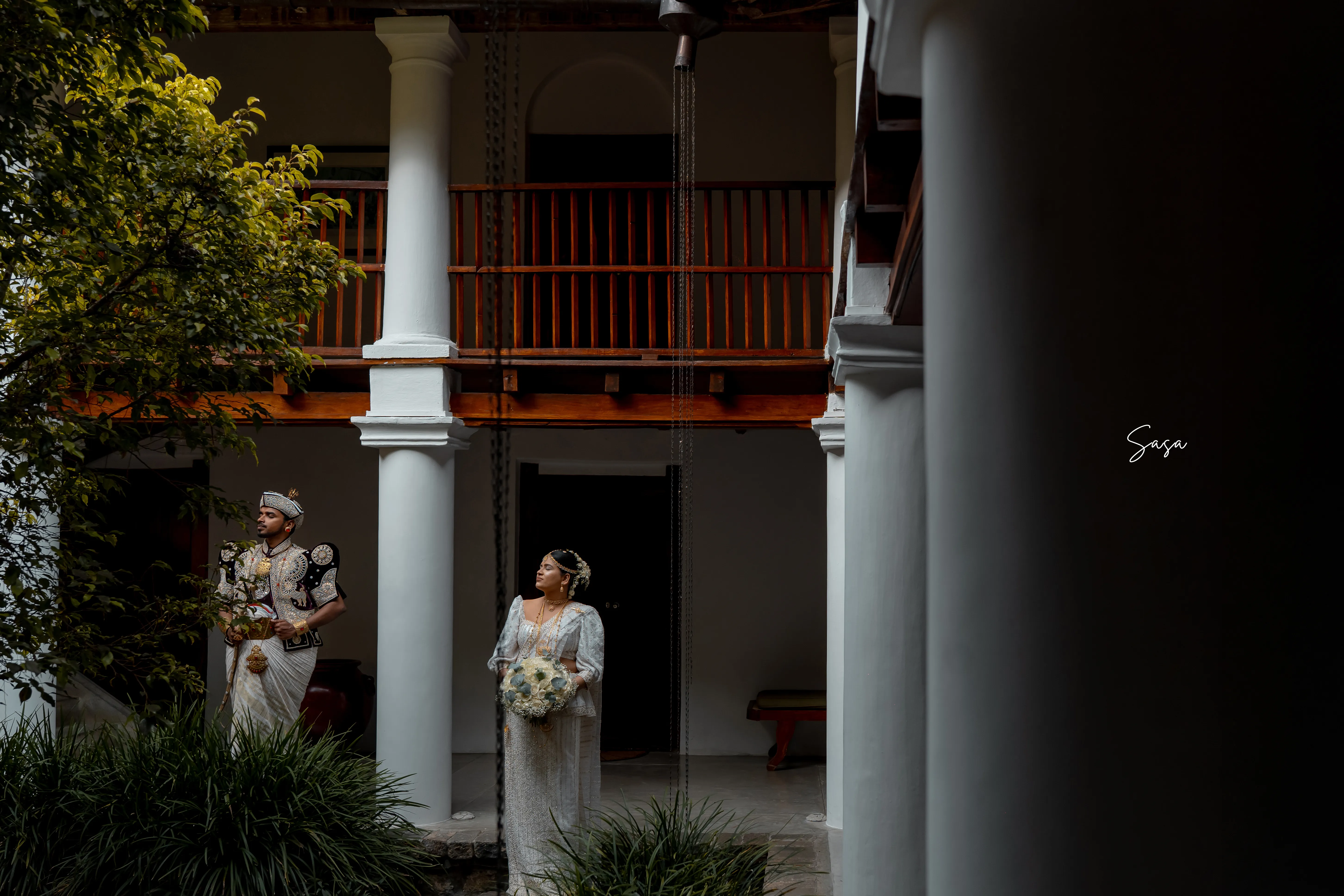 The couple stands on separate levels of the manor’s open courtyard.