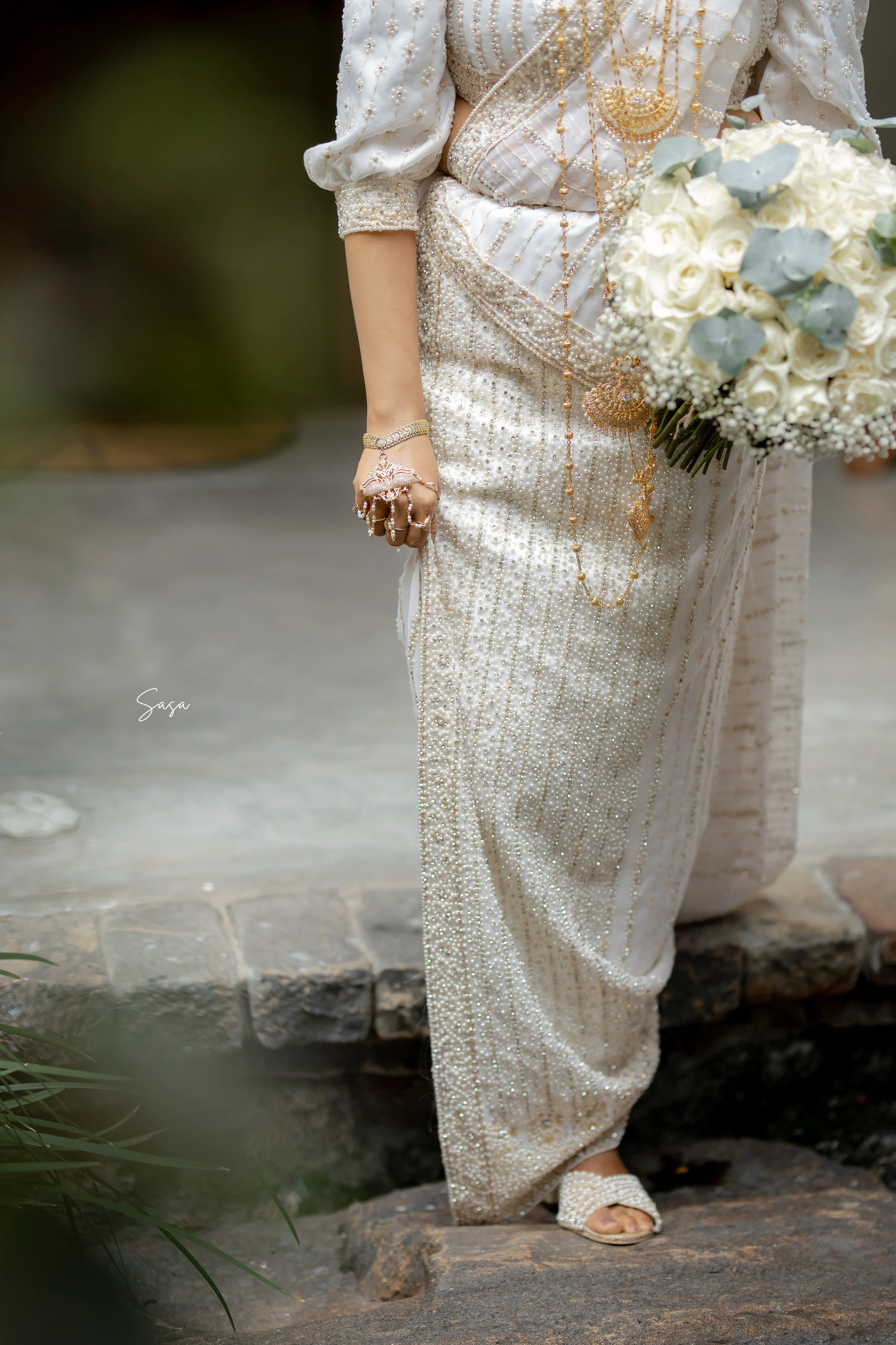 Nimasha’s beaded sleeve, bouquet, jewelry, and ivory fabric fill the frame.