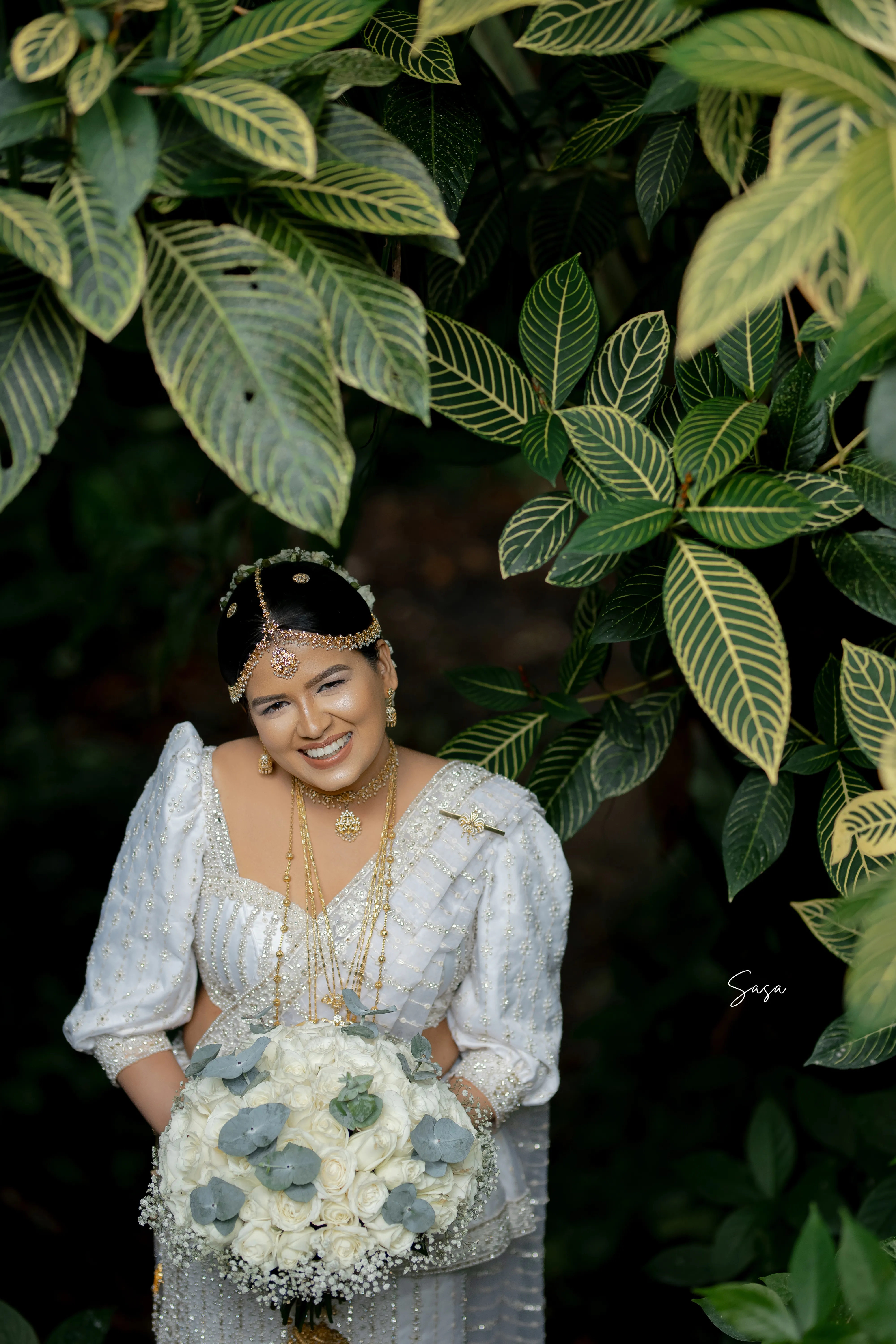 A close crop highlights Nimasha’s bouquet, gold necklaces, and embroidered dress.
