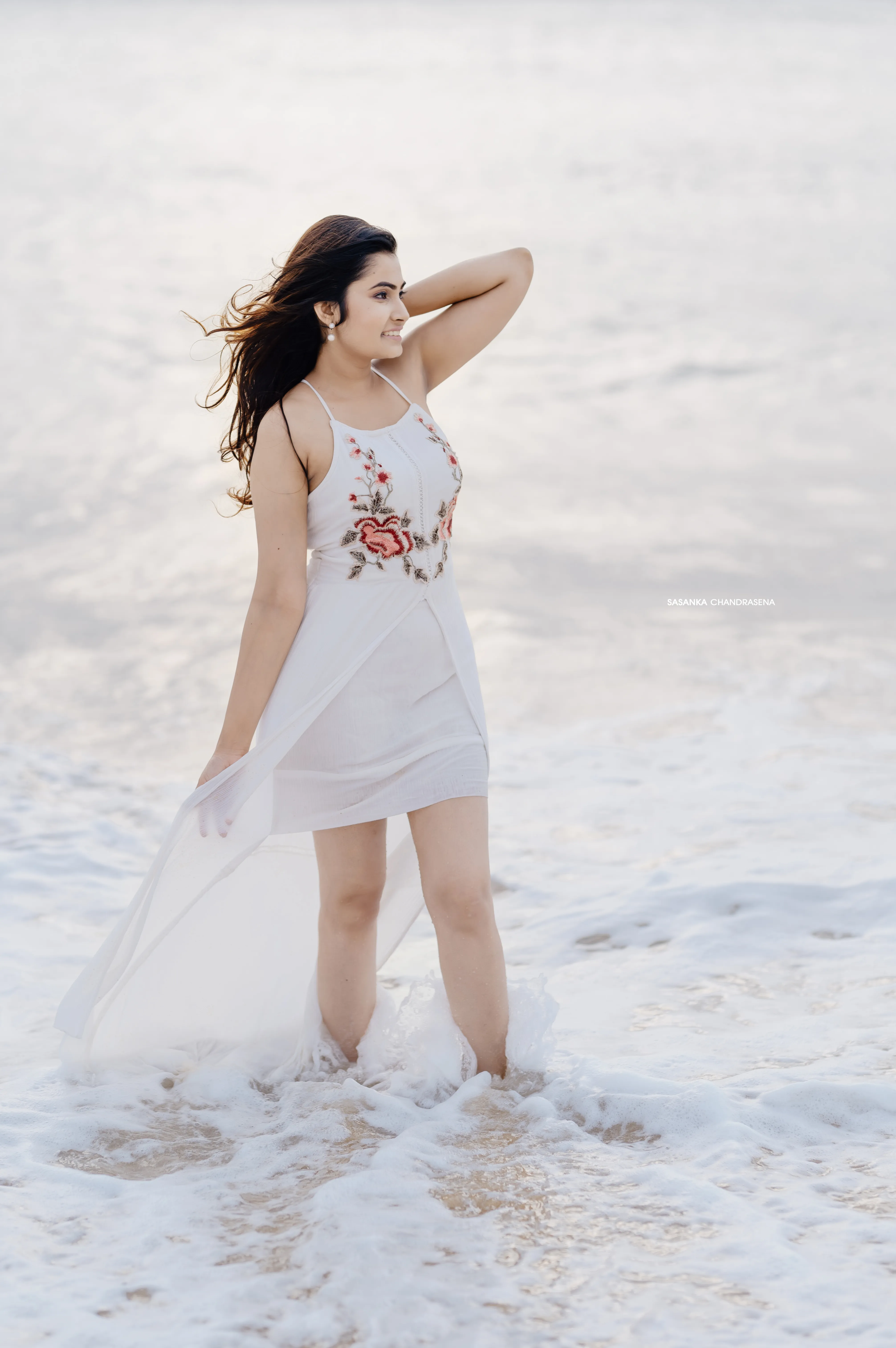 Coastal wind moves through Warunima’s hair in a bright beach portrait.