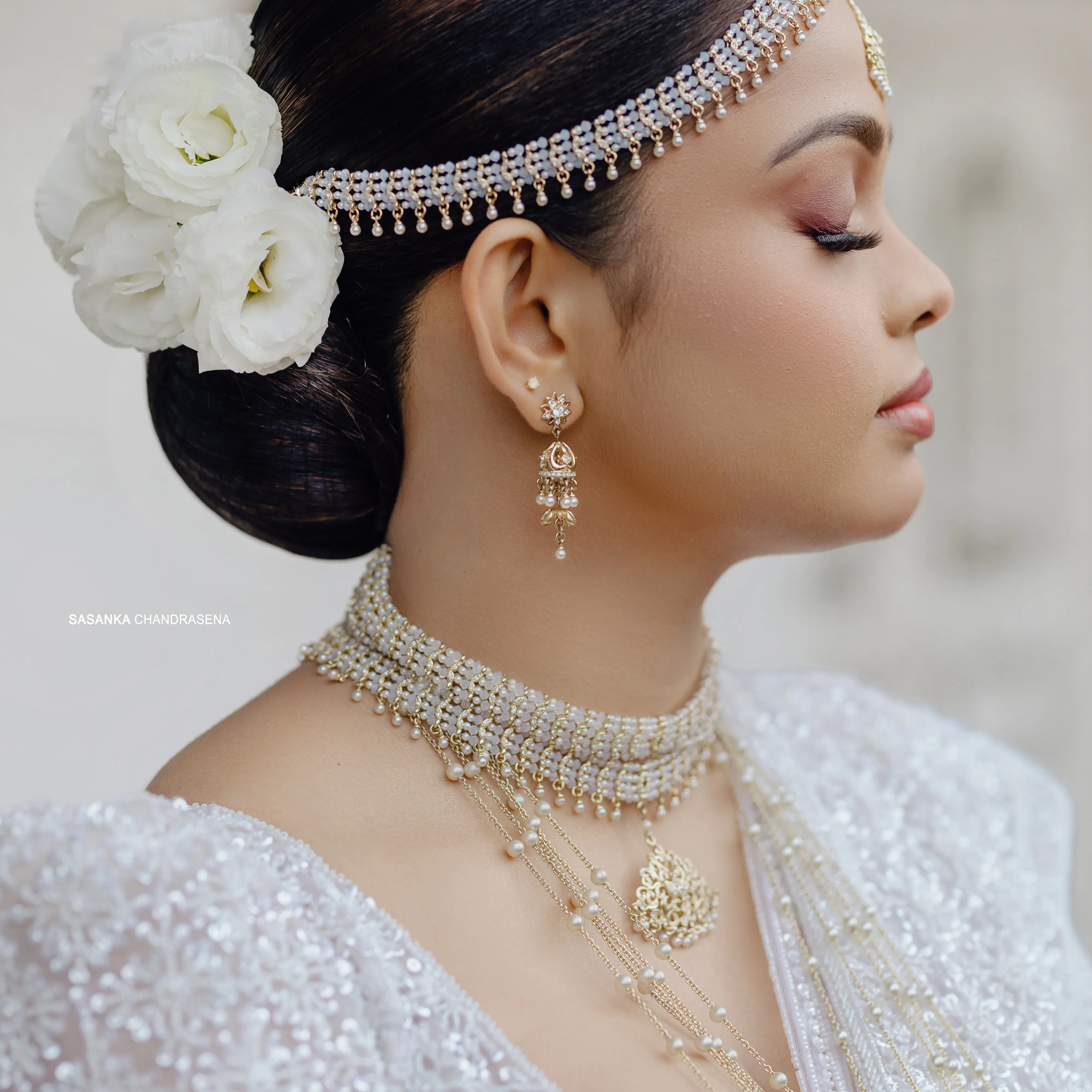Tharu’s floral hairpiece and silver jewelry fill a serene profile portrait.