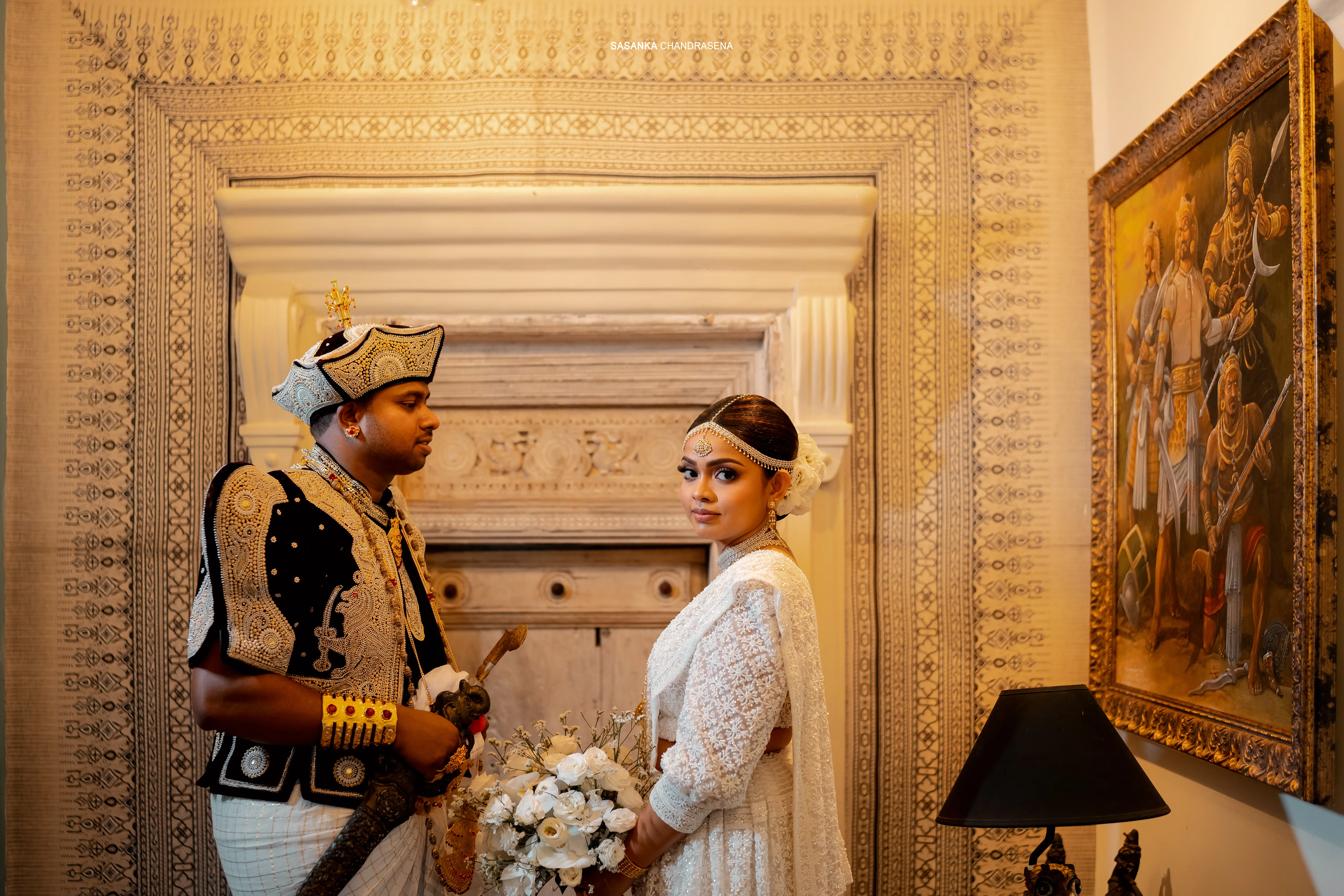 The couple stands among ornate frames and carved architectural details.
