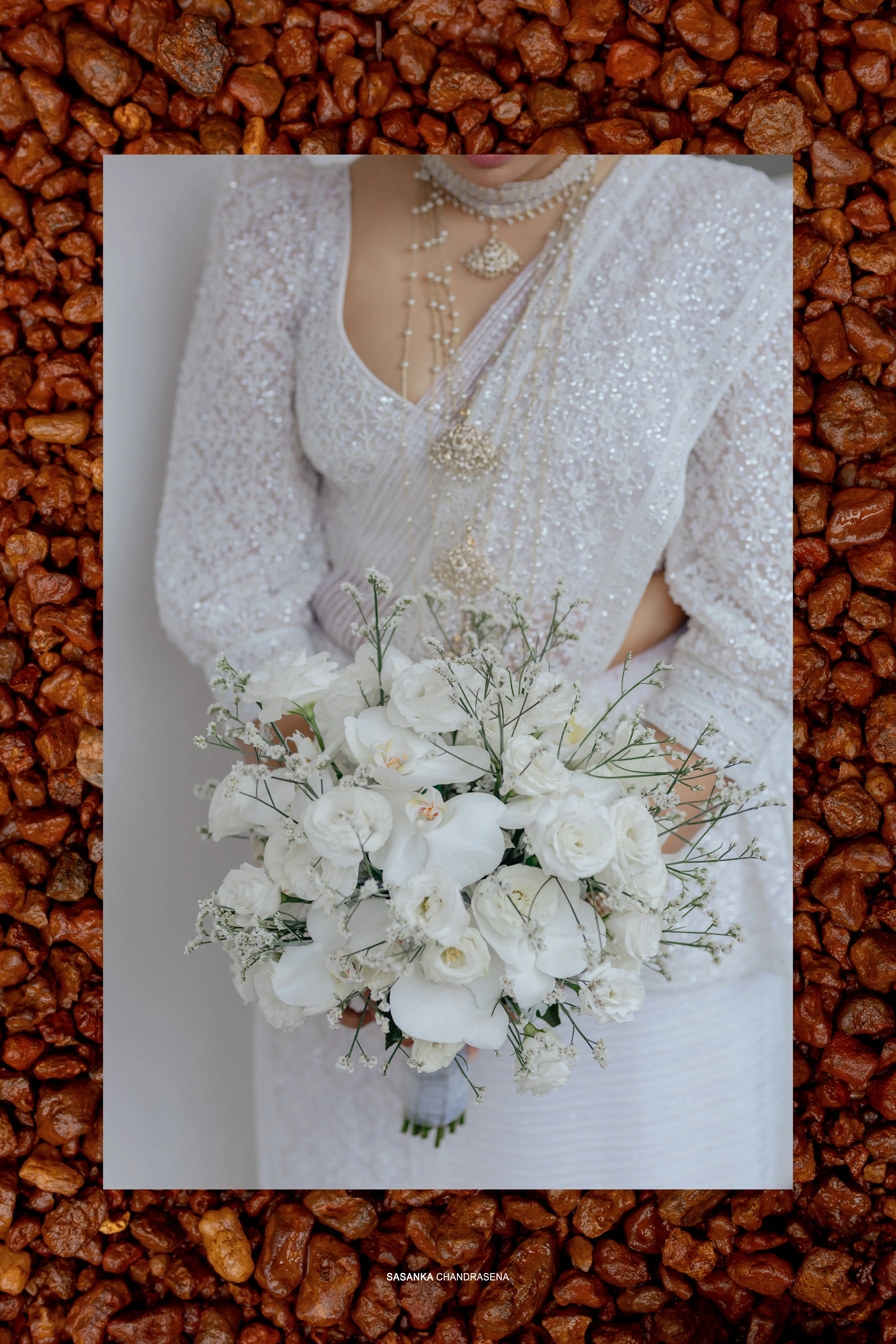 White orchids and lilies form an elegant bridal bouquet against warm texture.