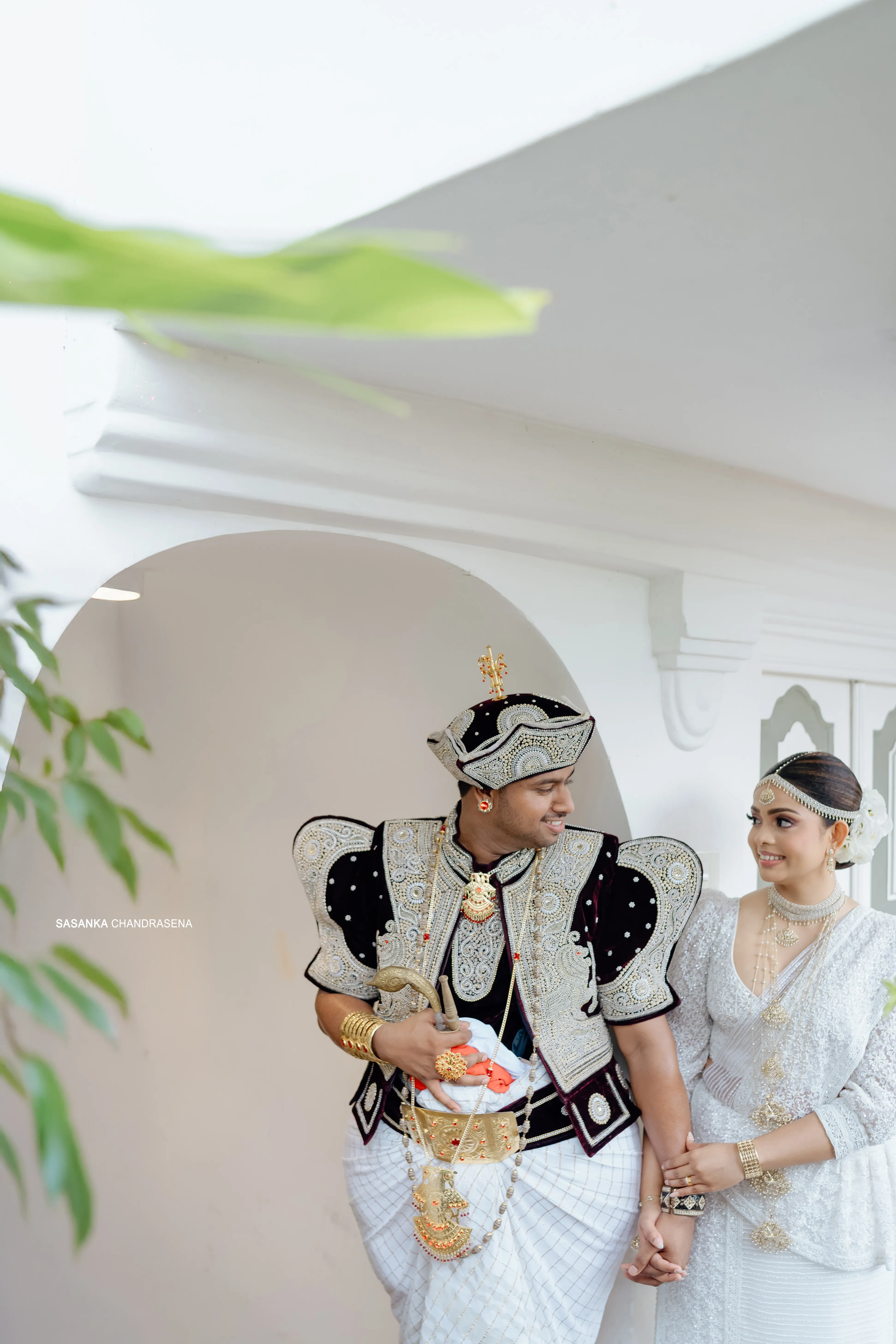 Tharu and Chandula smile at one another in ceremonial dress.