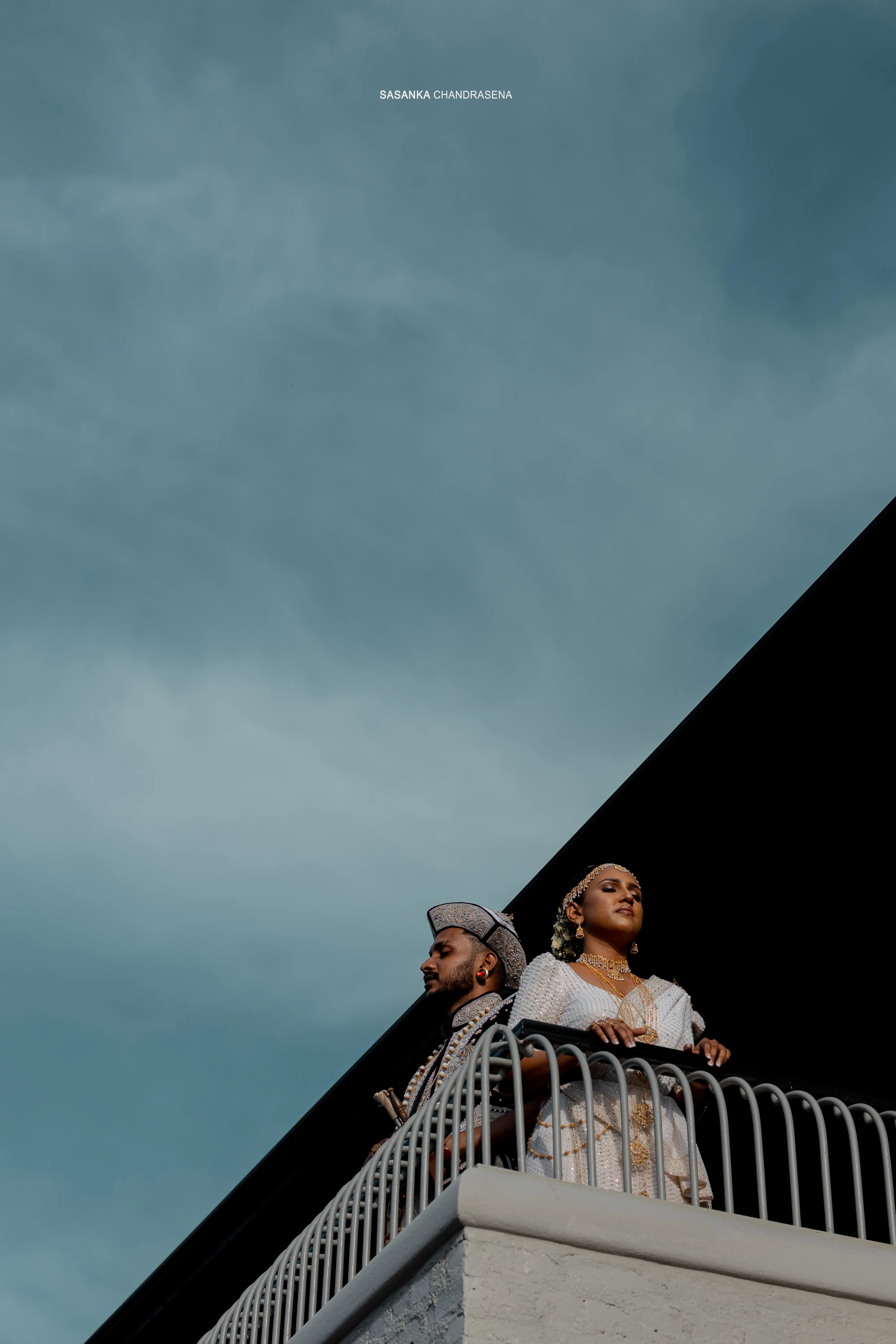 The newlyweds share a rooftop portrait against a deep blue sky.